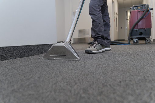 anonymous person cleaning a carpet with a steam machine