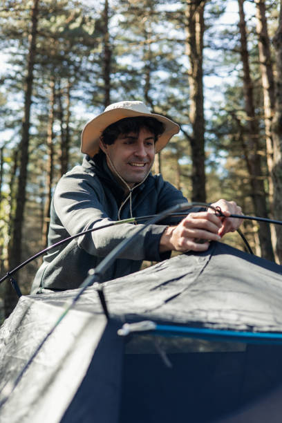 istock Young man assembling tent at campground during golden hour 2117963670