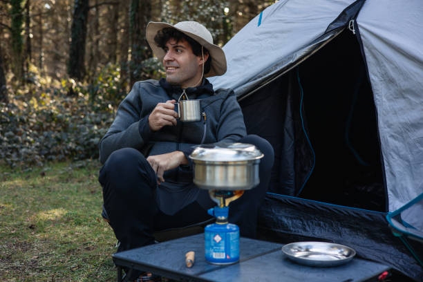 istock vertical portrait Camper Enjoying Coffee While Cooking Outdoors in Nature 2117964237