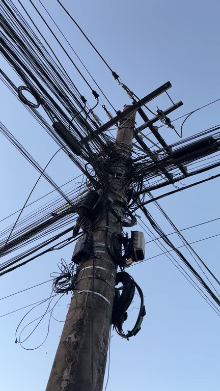 A dangerous lamp post with many electrical wires, close together