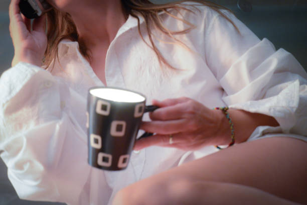 The female talks on her phone while holding a brightly lit cup.