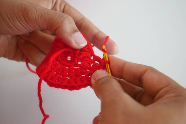 istock Hand close up crocheting with a pink hook, wool yarn, creative craft 2118000836