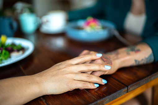 Close-up of a lesbian couple holding hands at coffee shop