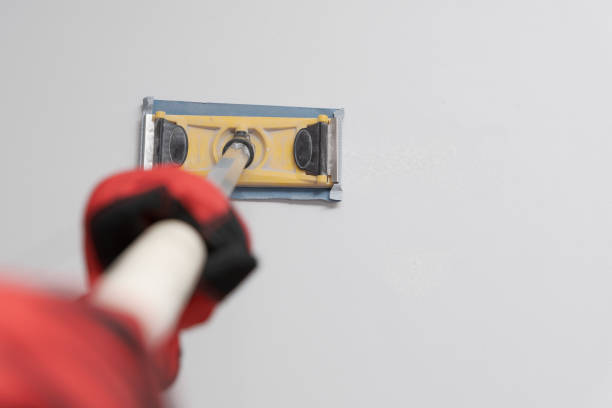 istock hands of a painter man wearing red gloves using a pole sander in a wall 2118015228