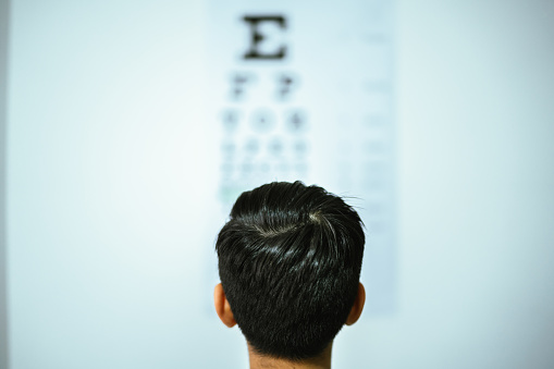 Child boy doing exam looking the eye chart at optics