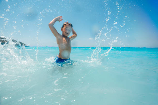 Boy enjoys playing with the waves on his summer vacation on the beautiful Greek Lefkada island