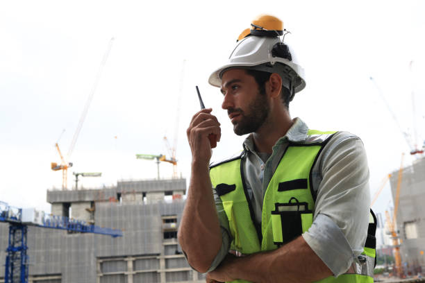 istock A skilled industrial engineer is effectively coordinating with his team at a construction site using a walkie-talkie for seamless communication. 2118046689