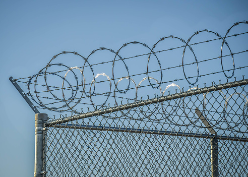 Metal fence with razor wire surrounds airport runway