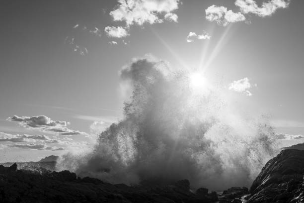 istock Waves crashing on cliffs in sunlight  in black and white 2118093541