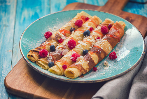 Homemade crepes with berries,coconut and strawberry syrup