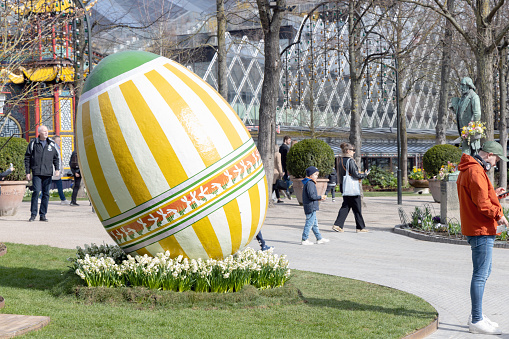 Large decorotive Easter egg on the grass in the park. Easter concept. Copenhagen, Denmark - March 28, 2024