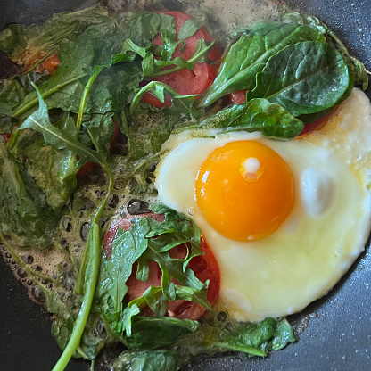 Egg and greens frying in pan