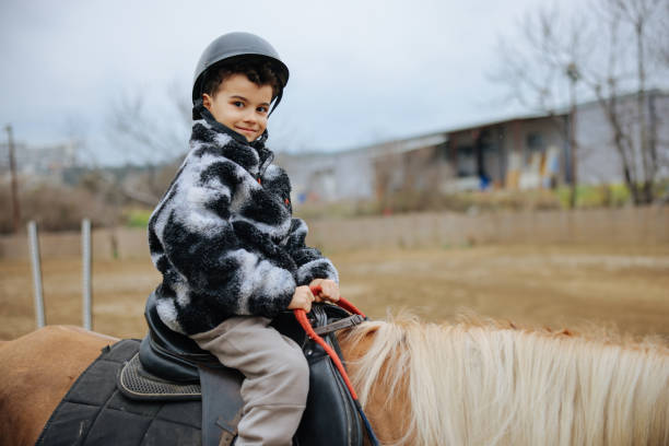 Ranch, happy and boy child on a horse to practice riding for a championship, competition or race. Happiness, animal and kid with smile practicing to ride a pony pet on a field or farm in countryside