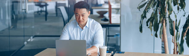istock Attentive asian businessman working on laptop at workplace in modern office 2118159111
