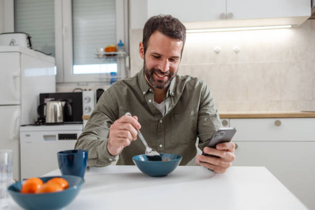 istock Mid adult man having a breakfast and using phone 2118171097
