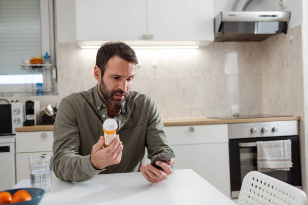 istock Man holding a pill bottle and a phone - Uncertainty 2118171602