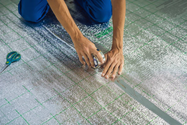 istock Master installs the overlapping thermal insulation in the room. Floor heating installation. Male hand holds reinforced tape. Repair in the apartment, floor insulation 2118211328