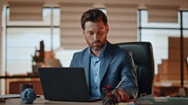istock Serious boss answering call corporate office. Smiling man talking mobile phone 2118232881