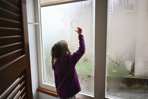 Child painting on wet window.