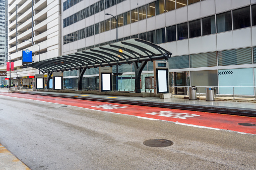 Deserted bus stop with blank billboards along a bus lane painted in red  in a downtown district on a rainy day. Chicago, IL, USA.