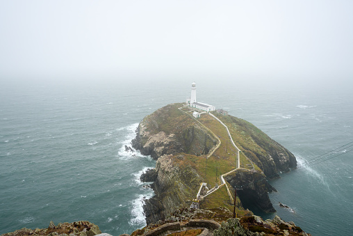 Historic South Stack lighthouse on the top of a small Island off the coast of Wales on a foggy summer day. Holy Island, Anglesey, Wales