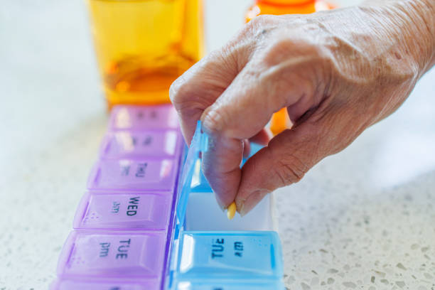 istock Senior hands with pill organizer. Elderly woman sorting medication for a week 2118272369
