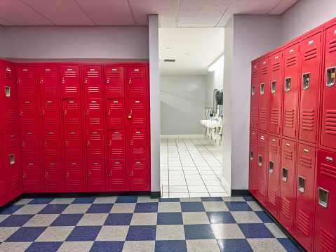 Locker room with red lockers and bathroom in a gym