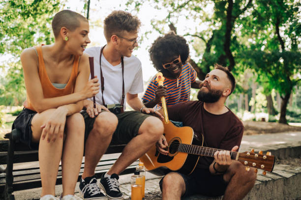 istock A small group of multicultural friends having fun with guitar in park. 2118397677