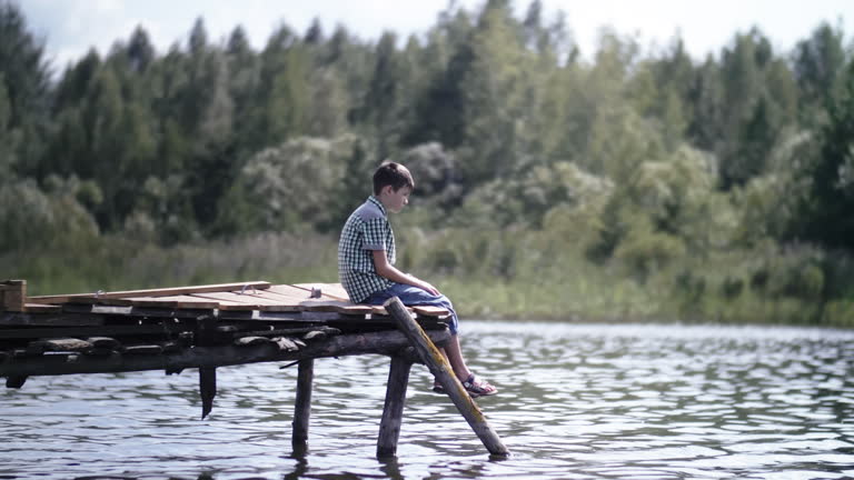 Reflections by the River: A Boy's Solitude on a Sunny Pier Amidst Deep Emotions