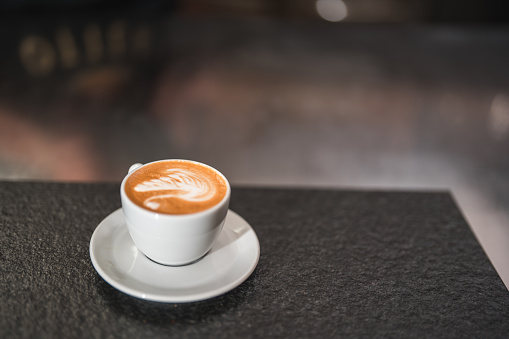 The elegance of latte art takes center stage as it graces the bar counter, where skillfully crafted coffee cups become a showcase of artistic talent in the coffee house.