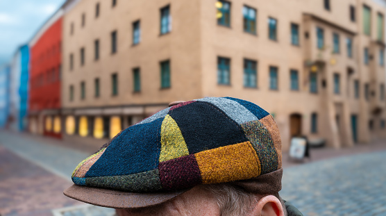 A colorful multicolored cap on the head of an unknown man with a blurred background of the ancient city of Wasserburg am Inn
