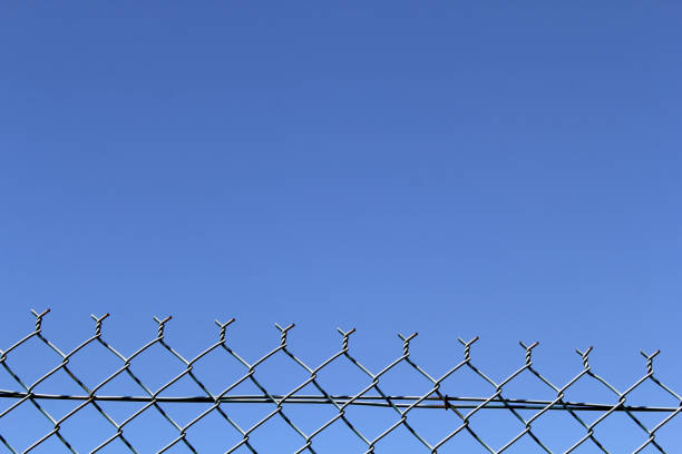 istock Chain-link fence against a blue sky background 2118437421
