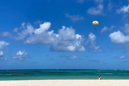 Yellow parasail over the ocean with view from beach.