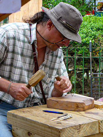 man carving a piece of wood at a street crafts fair