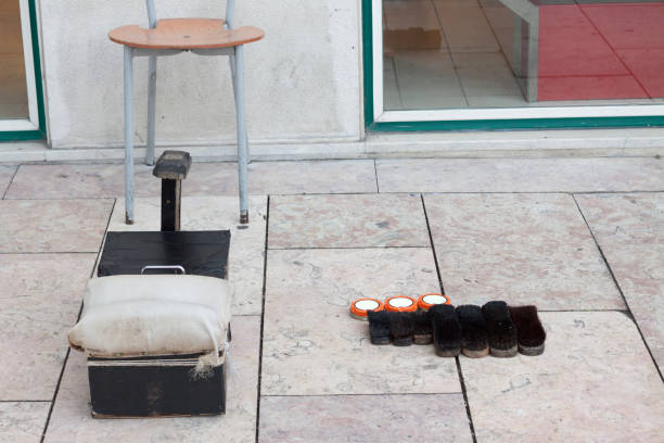 An informal shoeshine station laid out on a street in downtown Lisbon, Portugal. A seat for the customer, a seat at a lower level for the showshiner and a support for the customer to place his foot with the shoe to be polished. To the right hand side, brushed and tins of polish are laid out.