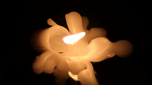 Heavily Melted Burning White Candle with Black Background