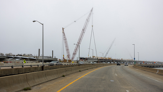 Tower cranes working along the misty Berkley Bridge with sparse traffic, on Elizabeth River in Norfolk, Virginia