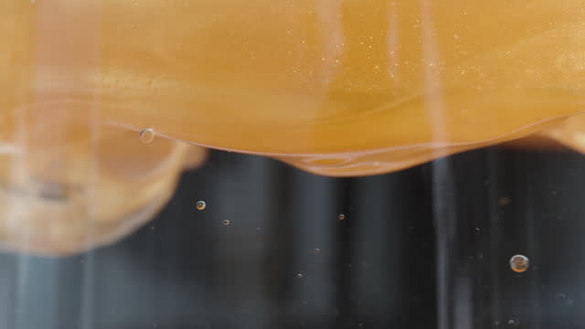Golden Liquid in Water, Different Densities Do Not Mix Together. Macro Chemical Process.
