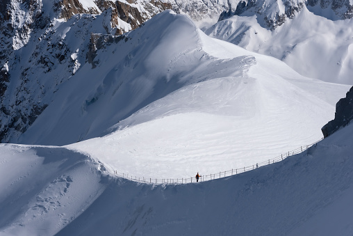 A single skier in silhouette standing on the ridge leading from the Aiguille du Midi to the Vallee Blanche in the Mont Blanc massif in Chamonix in France