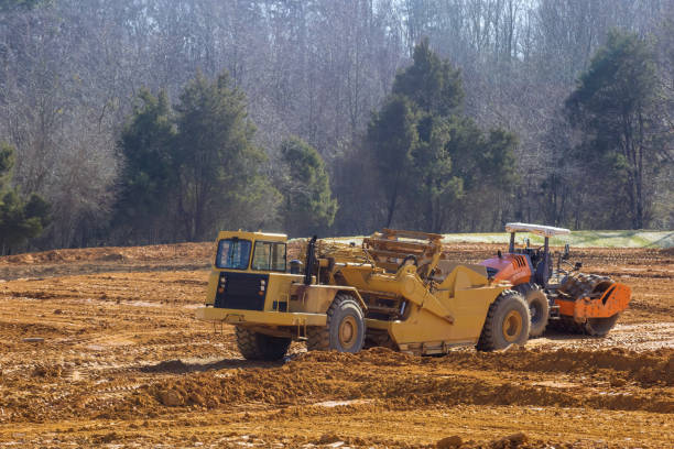 A yellow dump truck is driving and working in gravel pit