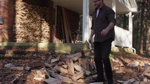 Firewood splitting. Mature lumberjack prepares firewood for winter in the house yard in autumn