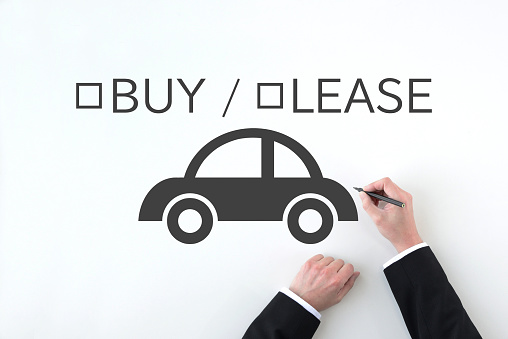 Business man’s hand drawing car pictogram and BUY / LEASE word