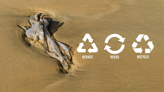 Reduce, reuse, recycle symbol on Plastic bag are left on the beach as waste polluting nature, ecological metaphor for ecological waste management and sustainable and economical lifestyle.