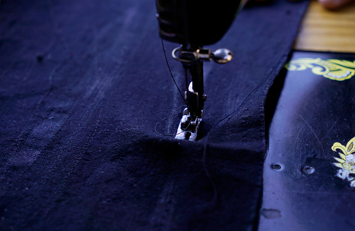 Close up photo of double needle sewing machine on navy blue fabric