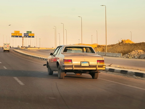 Cairo, Egypt, March 23 2024: an old vintage classic retro car of old times on its road in New Cairo city in Egypt, in a cross roads of fifth settlement, Shinzo Abe axis, marshal axis and ring road, selective focus