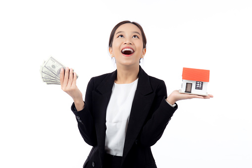 Portrait young asian businesswoman holding house and money for mortgage isolated white background, agent insurance business woman holding home for investment and presenting, business and finance.