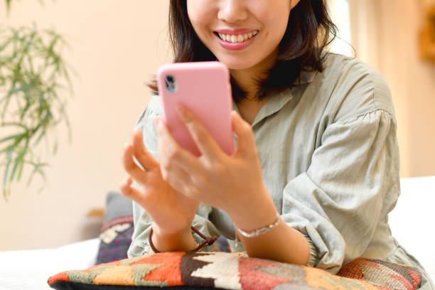 istock Asian young woman operating a smartphone at home 2118748739
