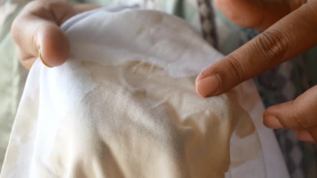 women holding white color dirty shirt, showing making stain