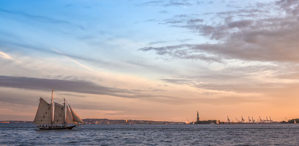 A sailboat sailing on the Hudson River at sunset.