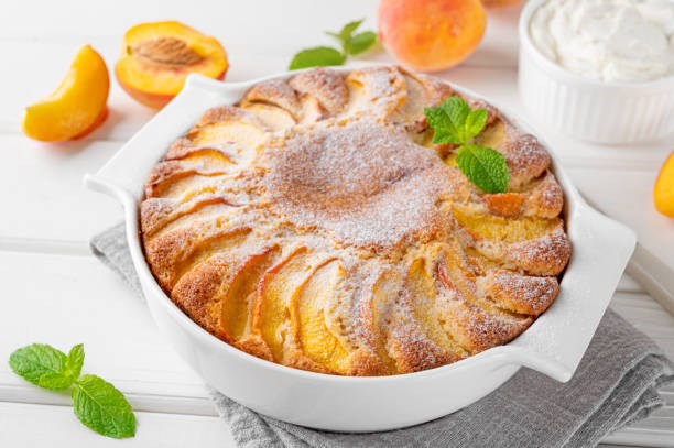 istock Delicious peach pie in a white ceramic baking form on a white wooden background. Summer cake. Selective focus, copy space. 2118783882